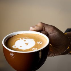 person holding a latte with latte art of a cure bear